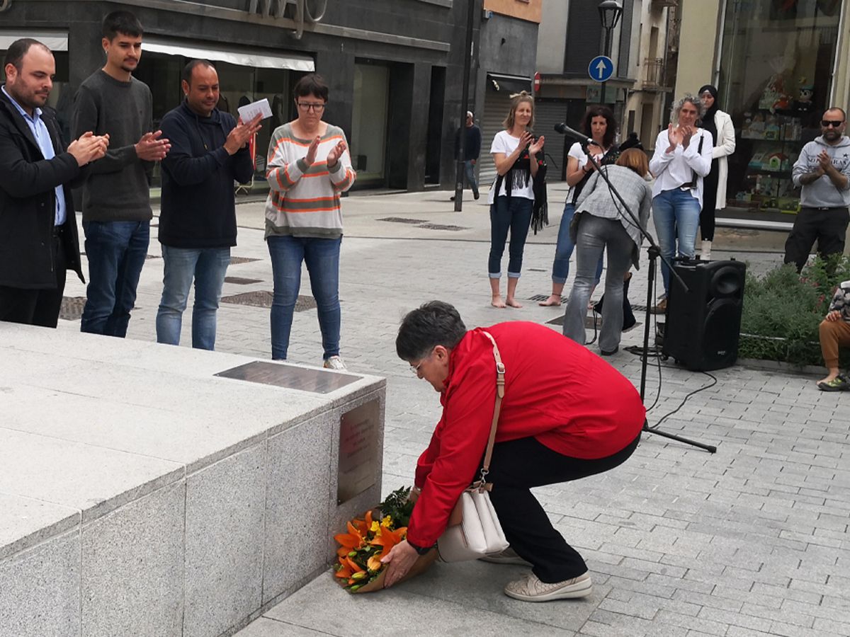 Una assistent diposita un rams de flors a la placa que recorda els vuit veïns de Sant Celoni deportats als camps nazis.