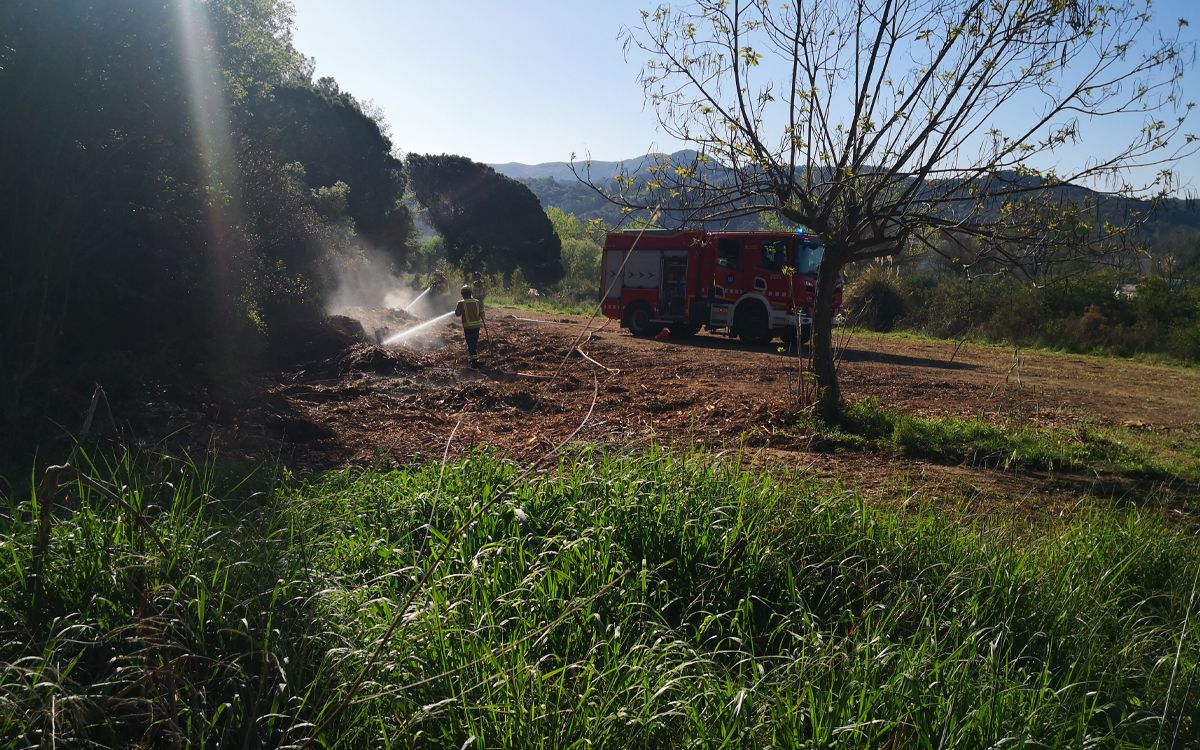Els bombers apagant les restes de poda en un terreny de Sant Celoni