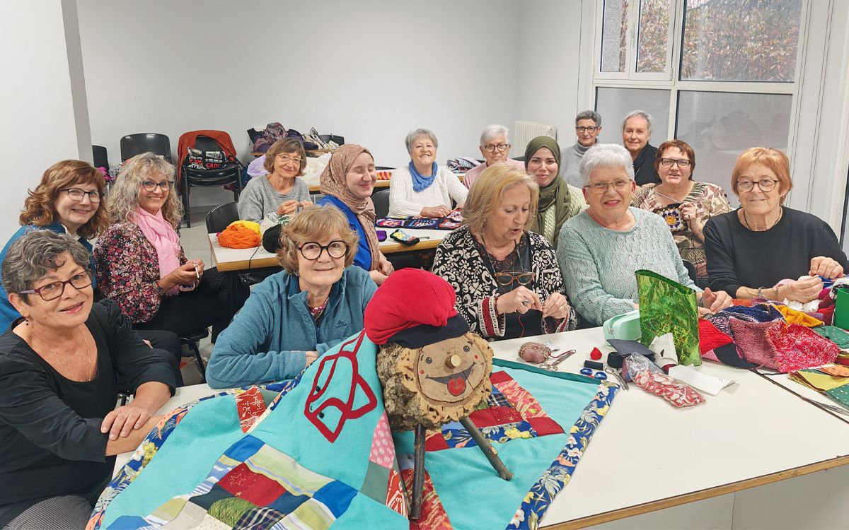 Dones voluntàries de Sant Hilari Sacalm enfilant les mantes per abrigars els tions.