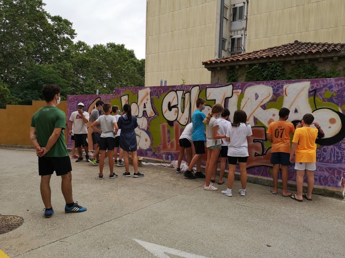 Els joves participants a l'Esplai Municipal d'Arbúcies han pintat el mural amb la frase la Cultura és lliure