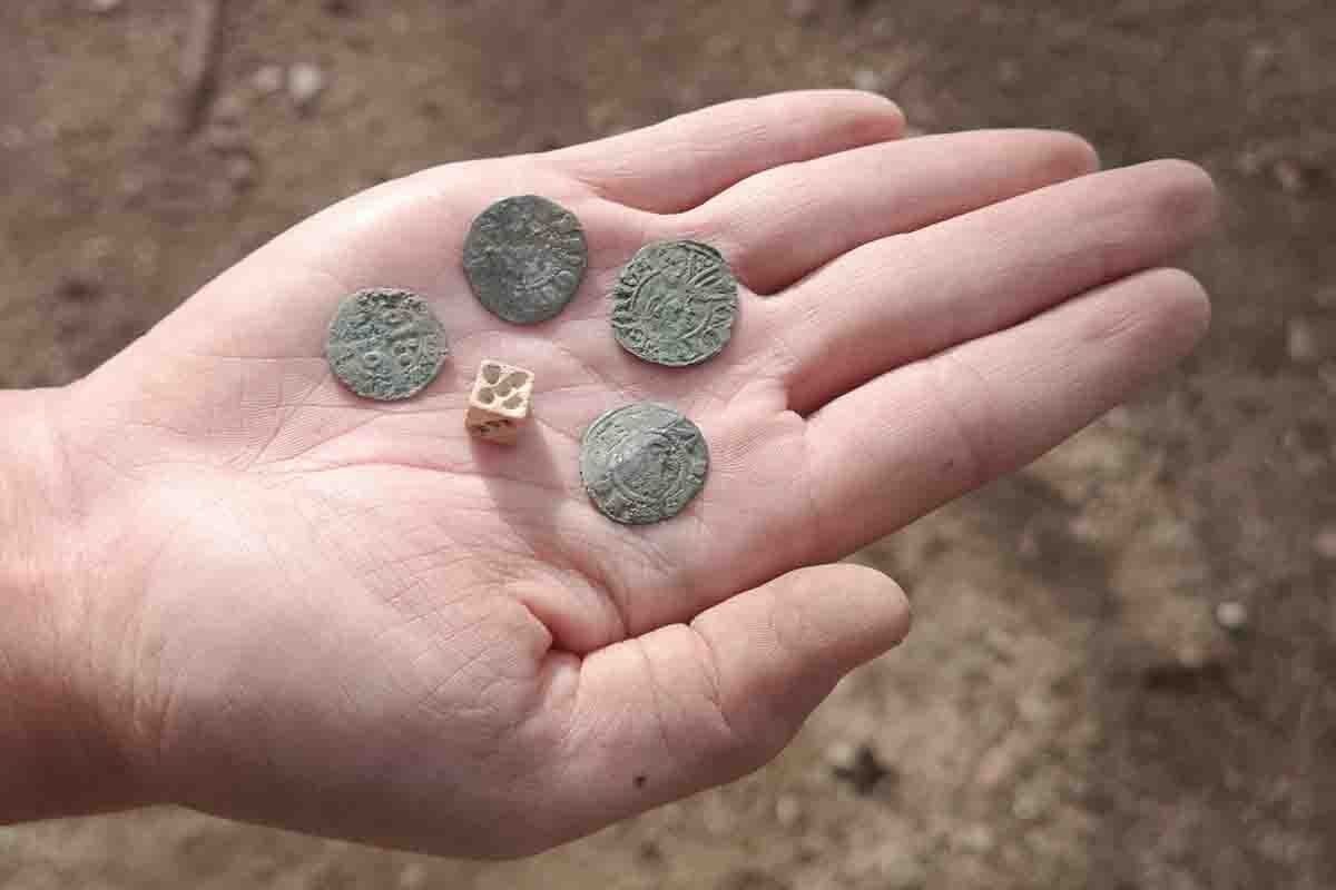 Algunes de les monedes i un dau d’os aparegut a les excavacions del castell de Montsoriu