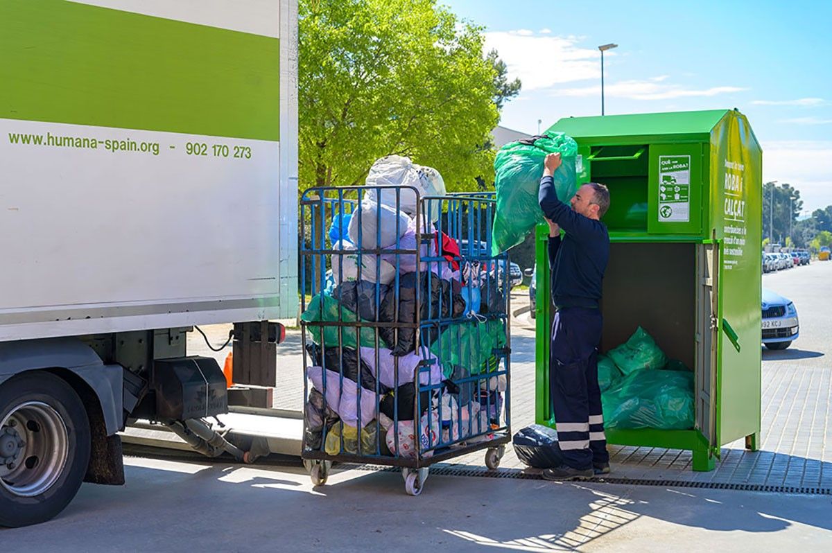 Un treballador d'Humana recull la roba dipositada en un contenidor