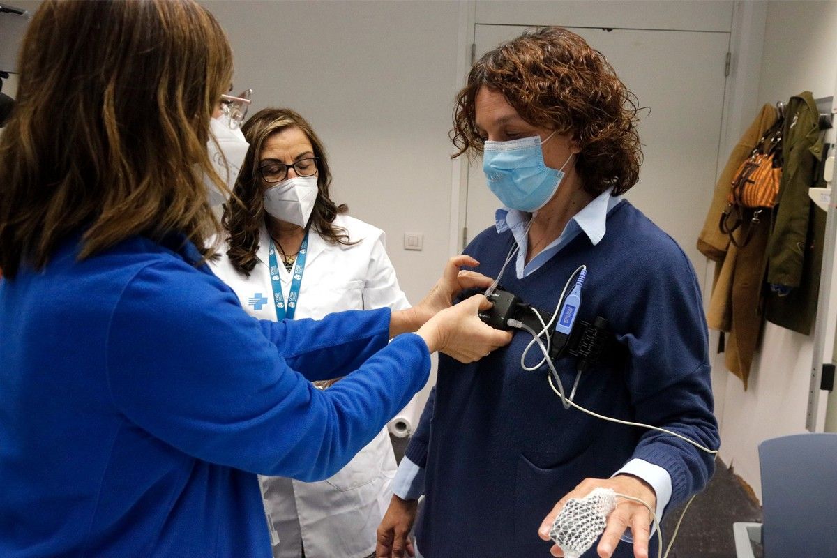 Dues infermeres ensenyen a una pacient d'apnea el funcionament d'un polígraf respiratori 