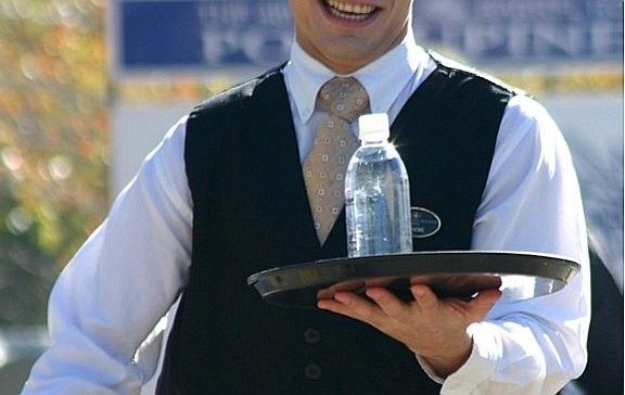 Un cambrer servint una ampolla d'aigua