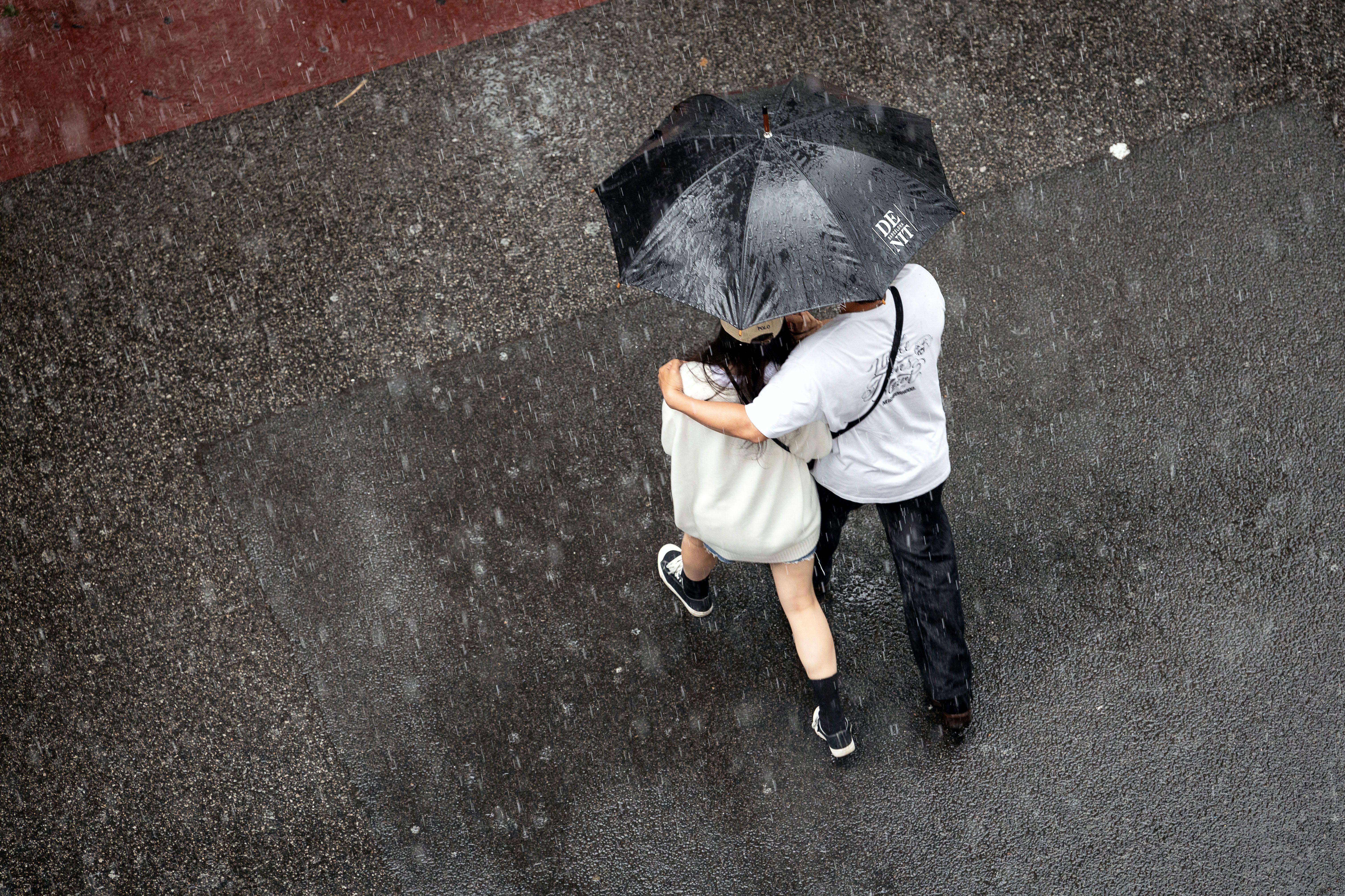 Dues persones es cobreixen de la pluja