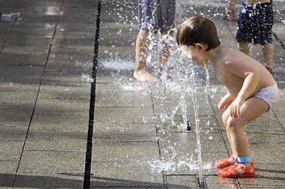 Un nen refrescant-se amb l'aigua d'una font.