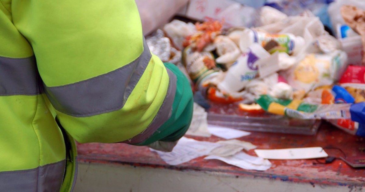 Operaris buscant papers que identifiquin les persones que han llençat les escombraries. 