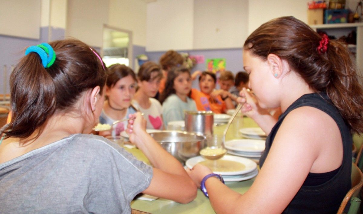 Nois i noies a l'hora de dinar al menjador de l'escola d'Avià.