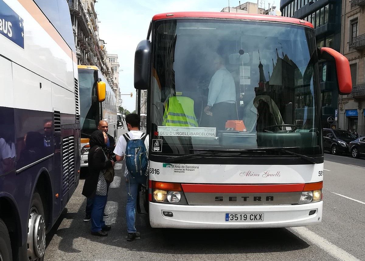 Passatgers pugen al bus des de l'asfalt al centre de Barcelona (arxiu).