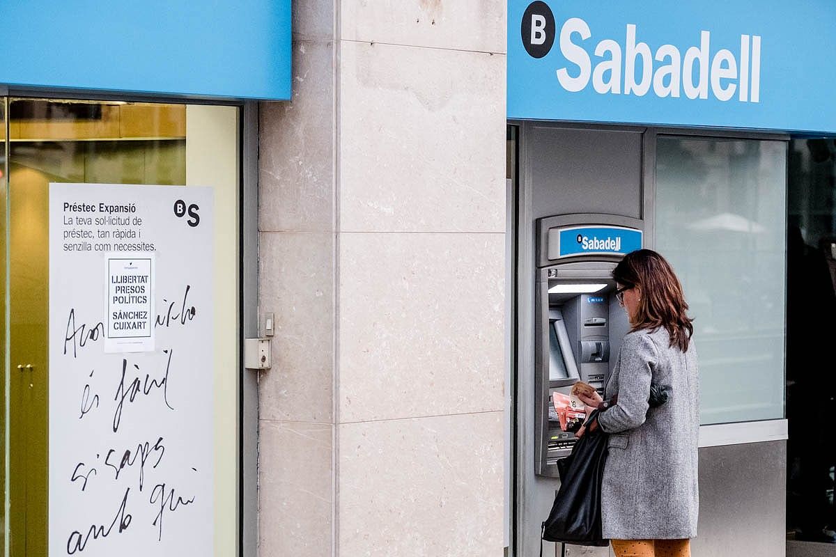 Una dona retira diners d'un caixer del Banc Sabadell.