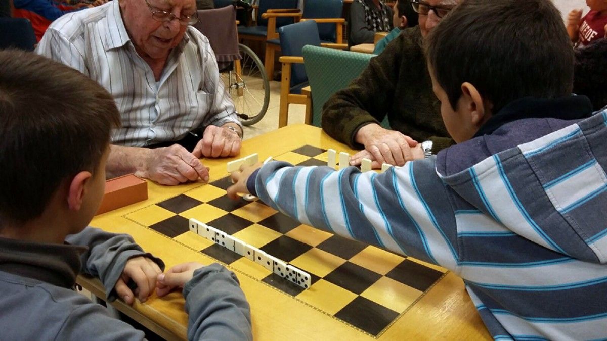 Gent gran amb infants del Centre Obert de Berga participant en un joc.