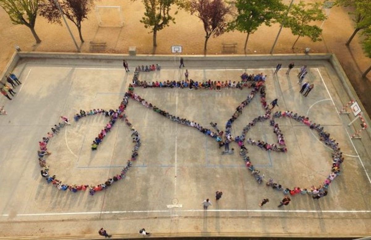 Els escolars que han participat al Dia Sense Cotxes han dibuixat una bicicleta gegant a l'escola Verntallat.