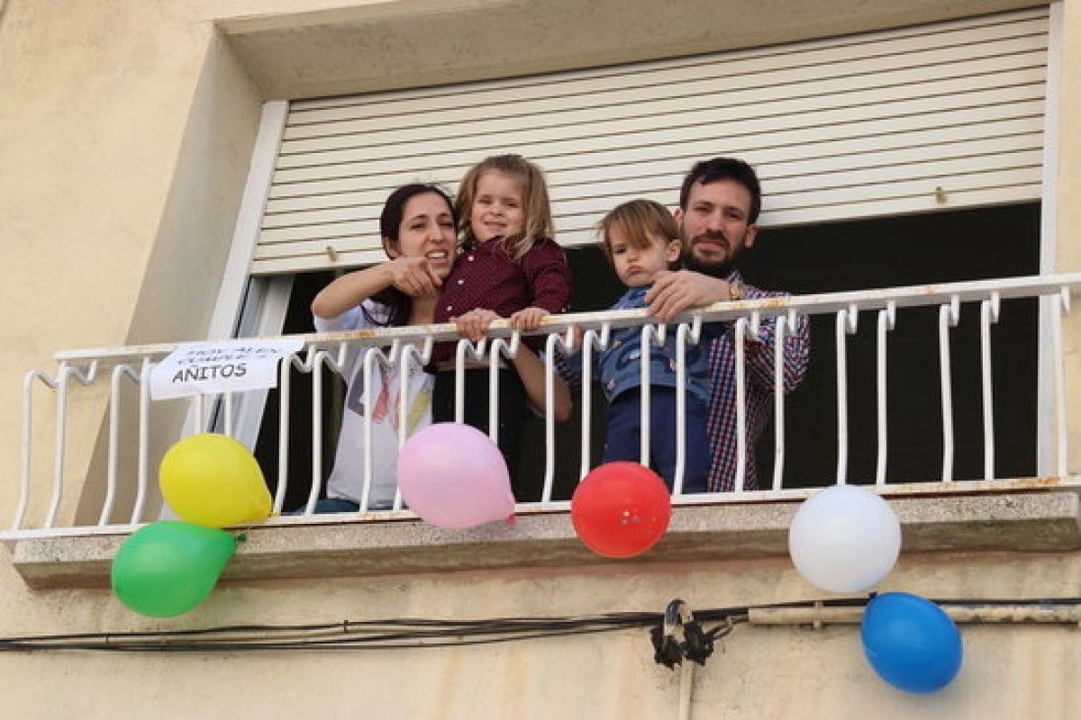 Una família celebra l'aniversari d'un nen des de la finestra de casa seva.