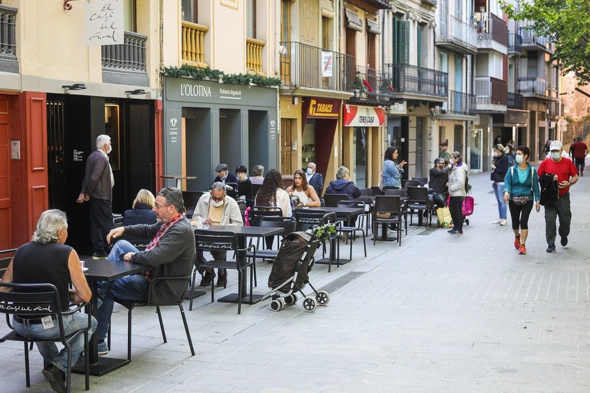 Al Firal d'Olot els ciutadans passegen o són asseguts a les terrasses dels bars.