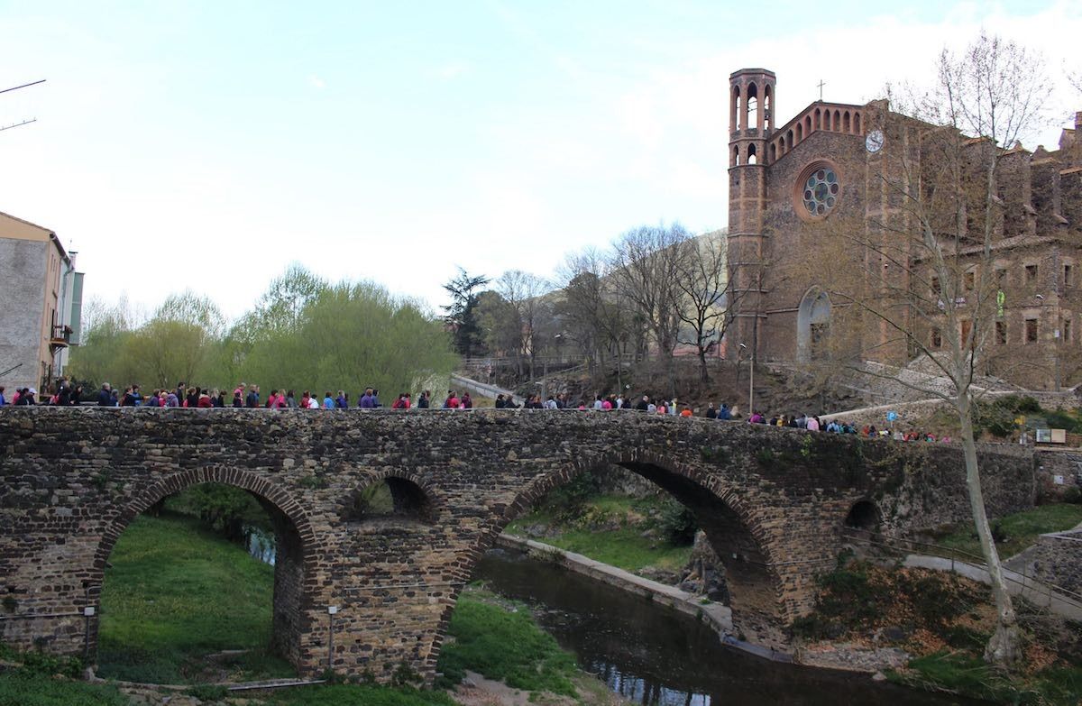 Els participants travessen el pont medieval durant la cursa solidària.