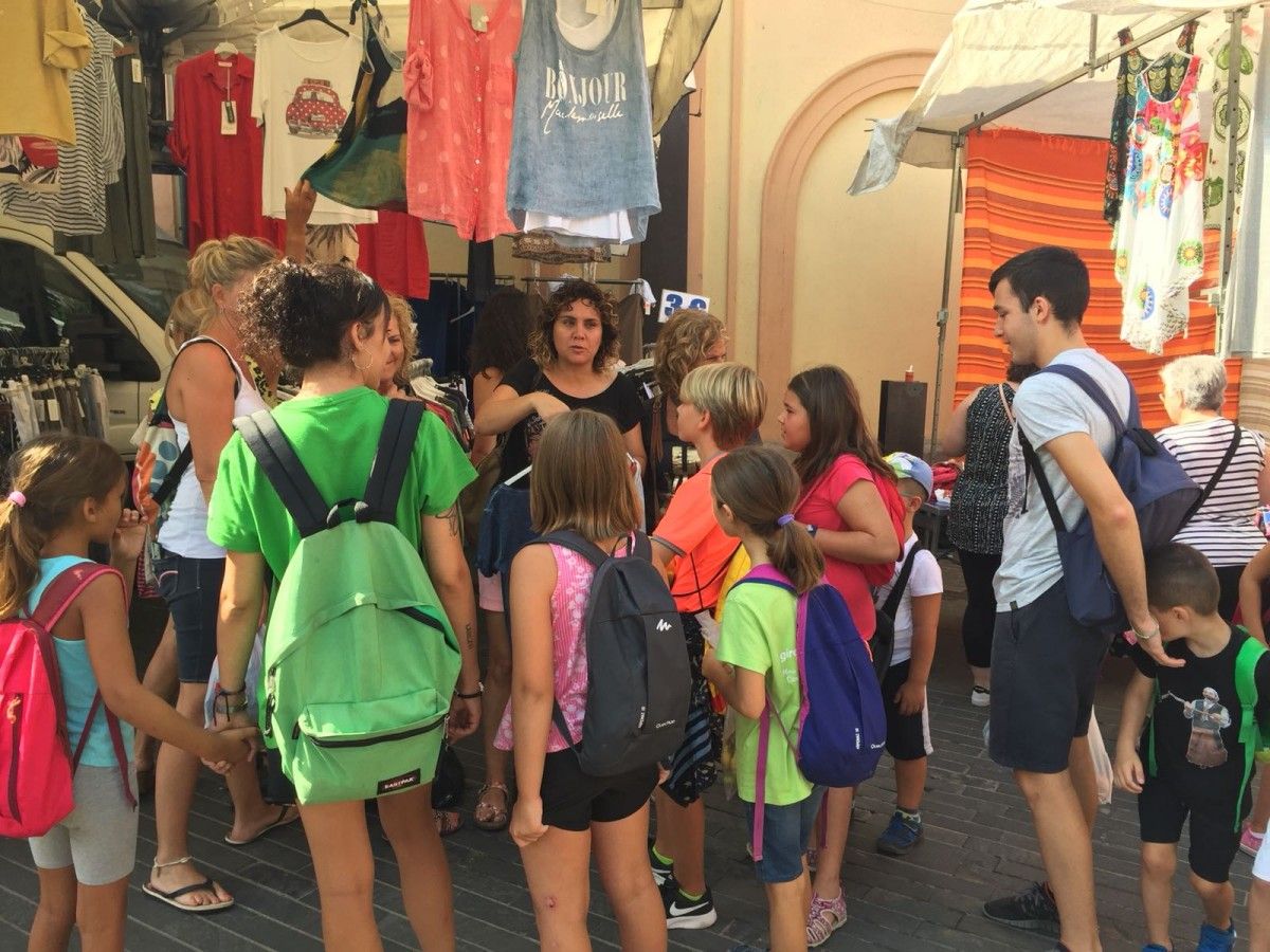 Els infants del casal d'estiu de Sant Privat d'en Bas en una pparada de roba al mercat setmanal d'Olot.