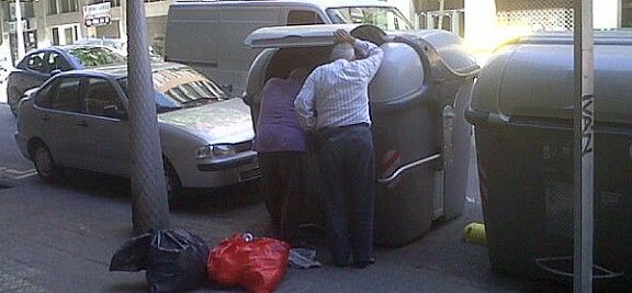 Dos pensionistes remenen un contenidor al carrer Dos de Maig de Barcelona.