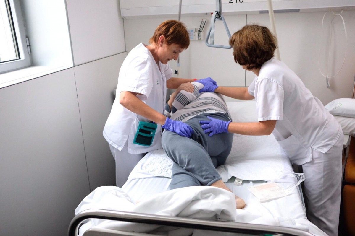 Unes infermeres posen unes turmelleres a un pacient de l'Hospital d'Olot per a evitar que s'ulceri la pell dels peus per pressió.
