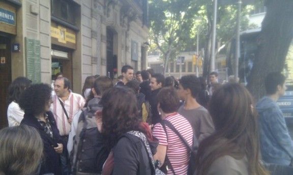 Desenes d'estudiants i usuaris esperant l'autocar a la parada de Pau Claris de Barcelona.