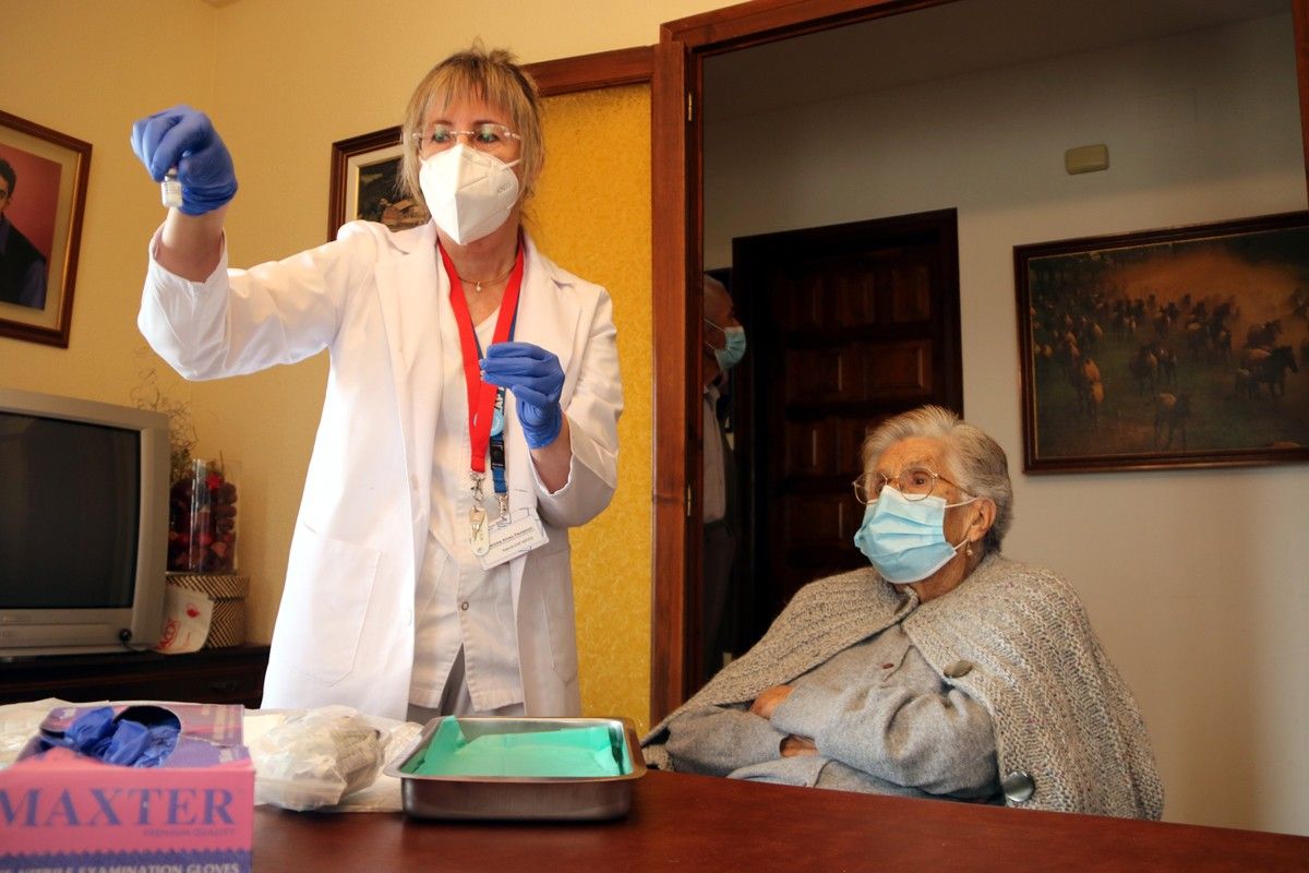 Concepció Capdevila i una infermera a punt de vaccinar-la al menjador de casa seva.
