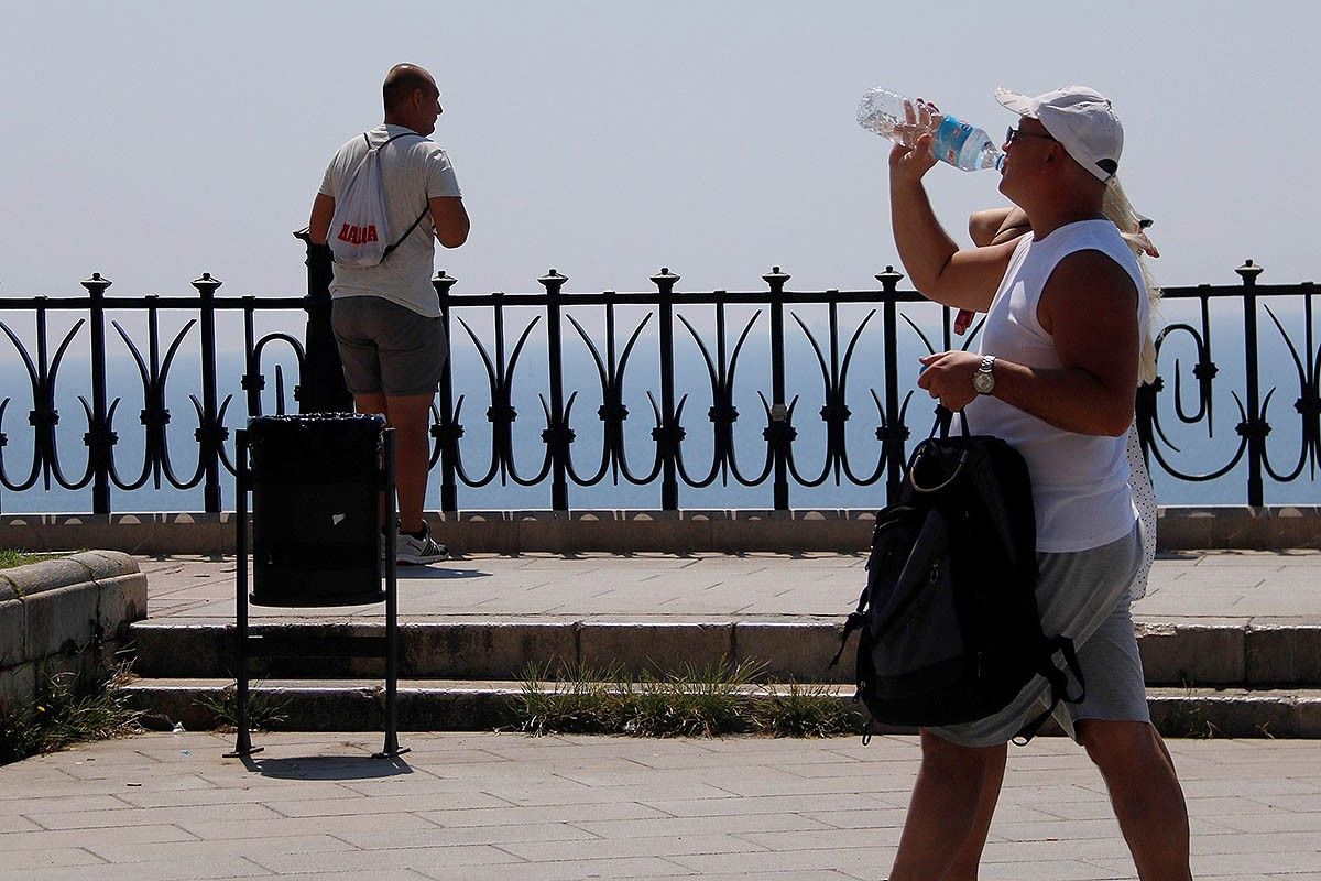 Un home beu aigua mentre passeja al Balcó del Mediterrani de Tarragona. 