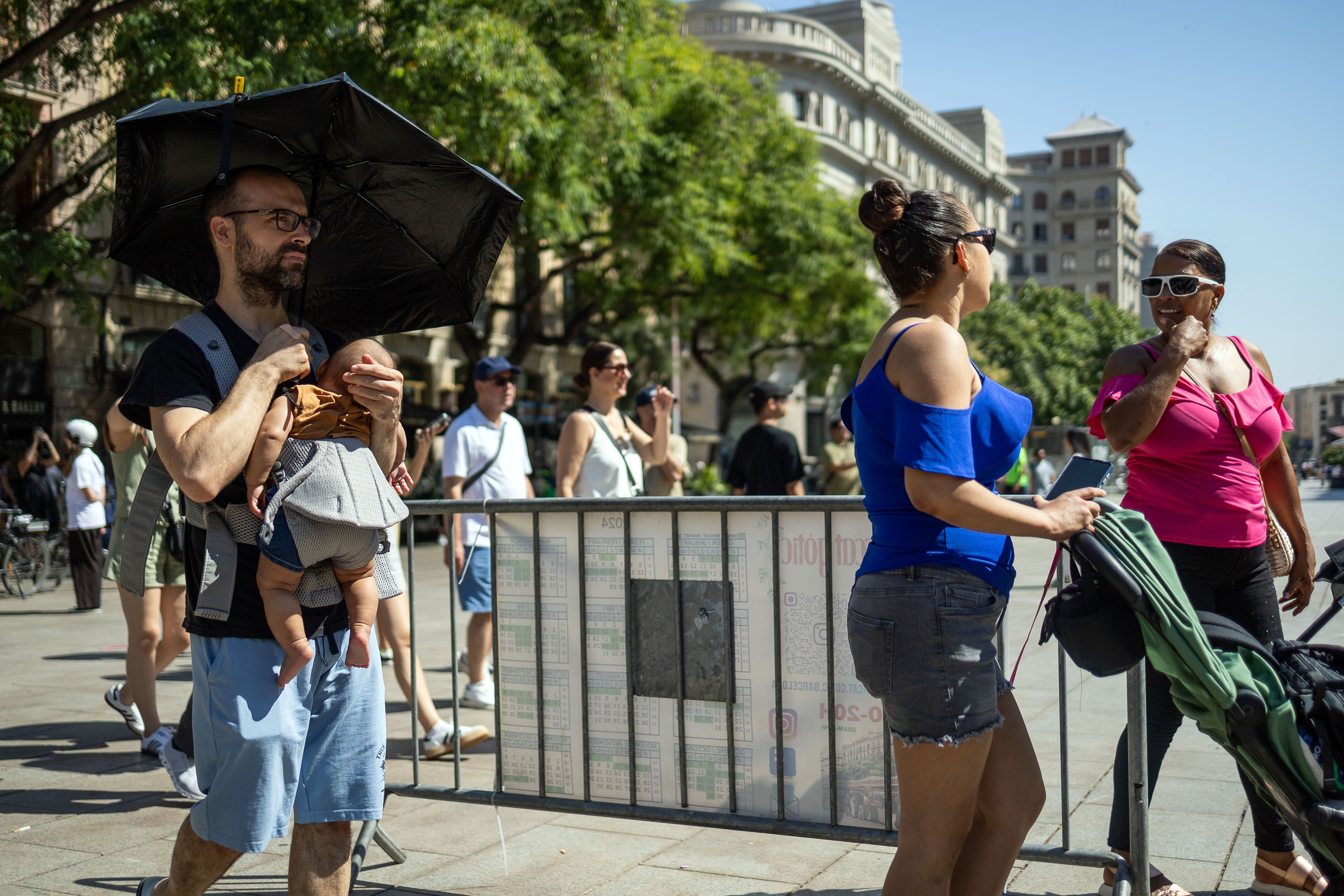 Un turista es protegeix del sol i la calor al centre de Barcelona protecció solar nadó