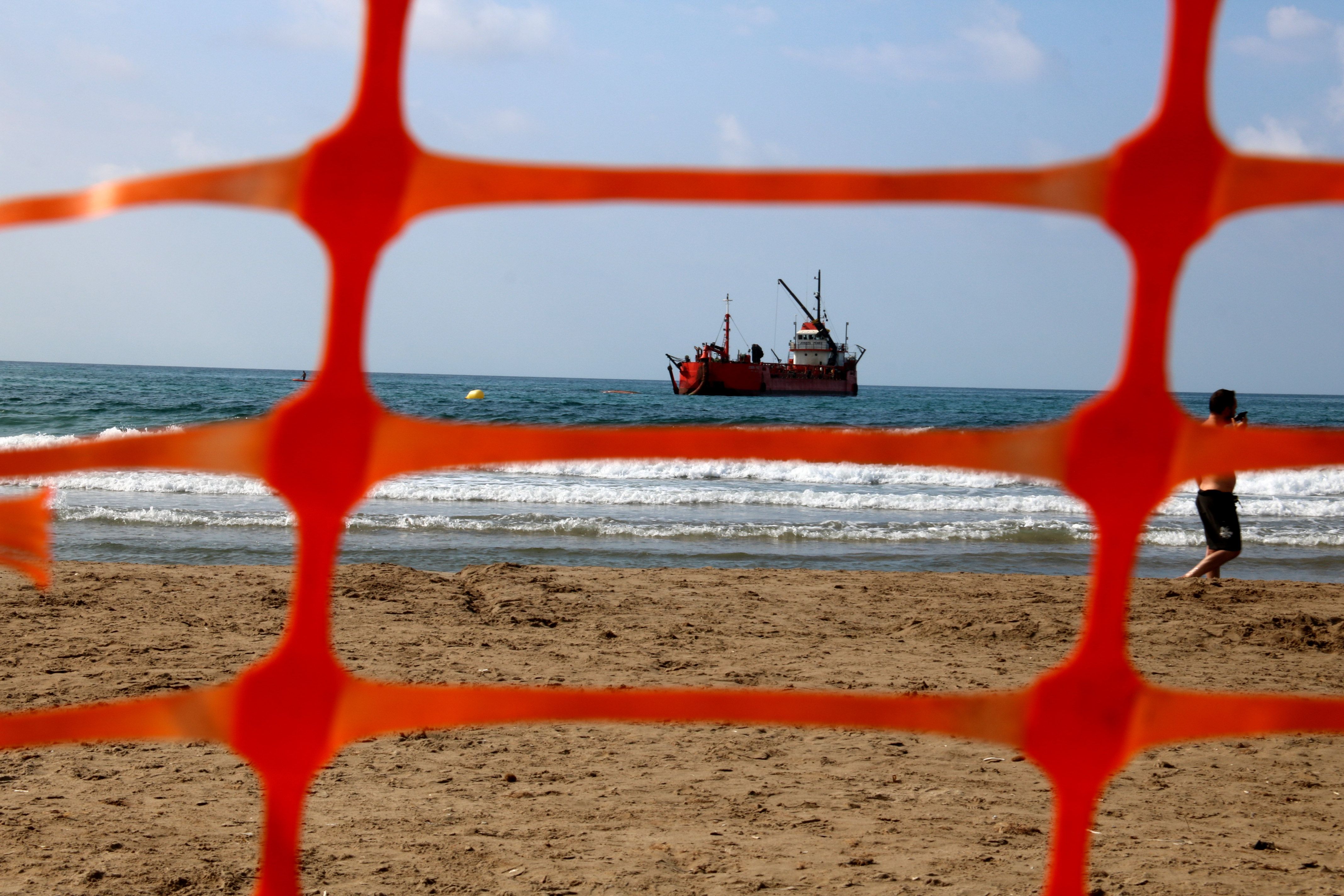 Una platja tancada mentre una draga hi aporta sorra