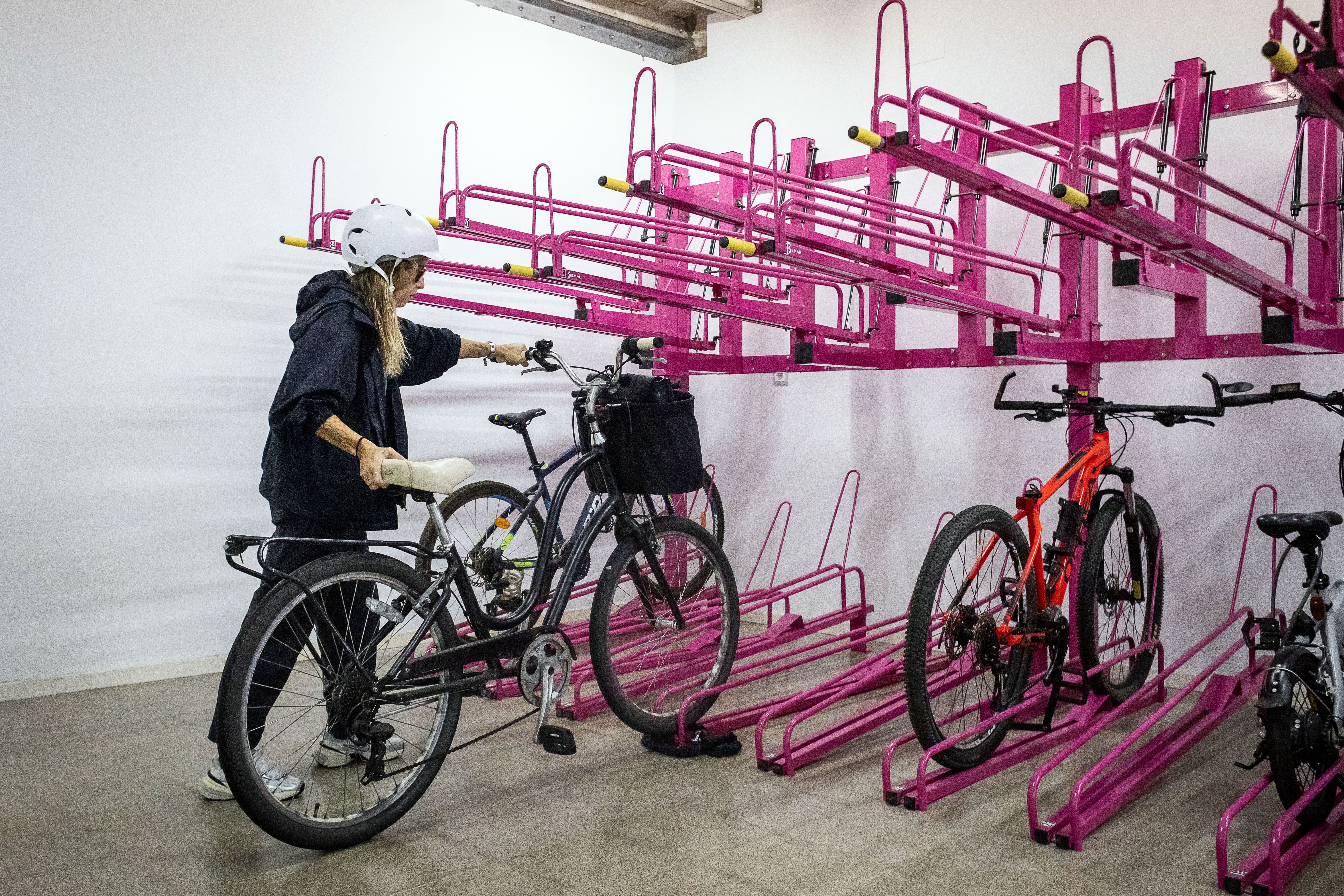 Una usuària guardant la bici a l'aparcament segur de bicicletes de Cúbic al barri de Gràcia