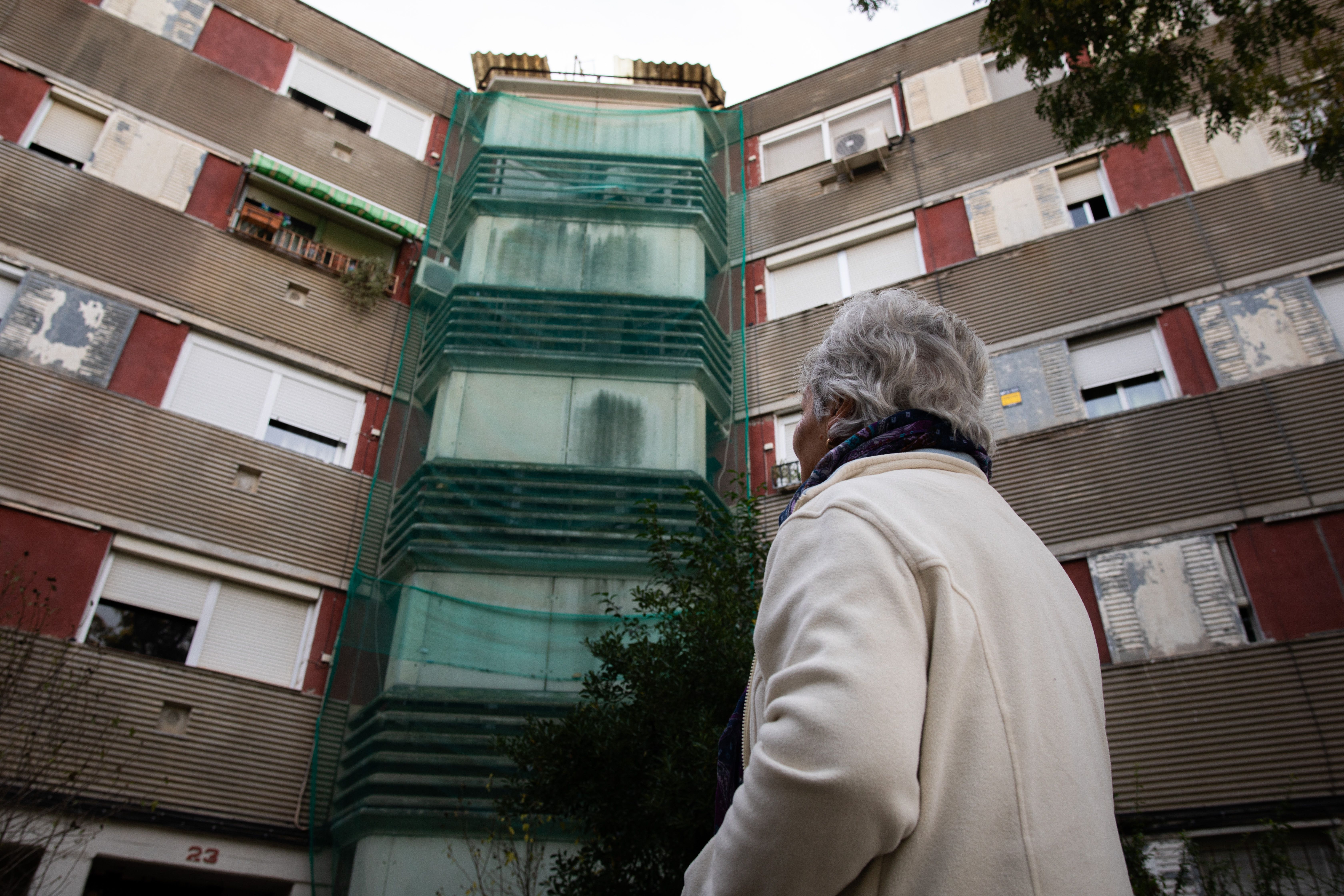 Una dona observant un edifici amb amiant amb mal estat