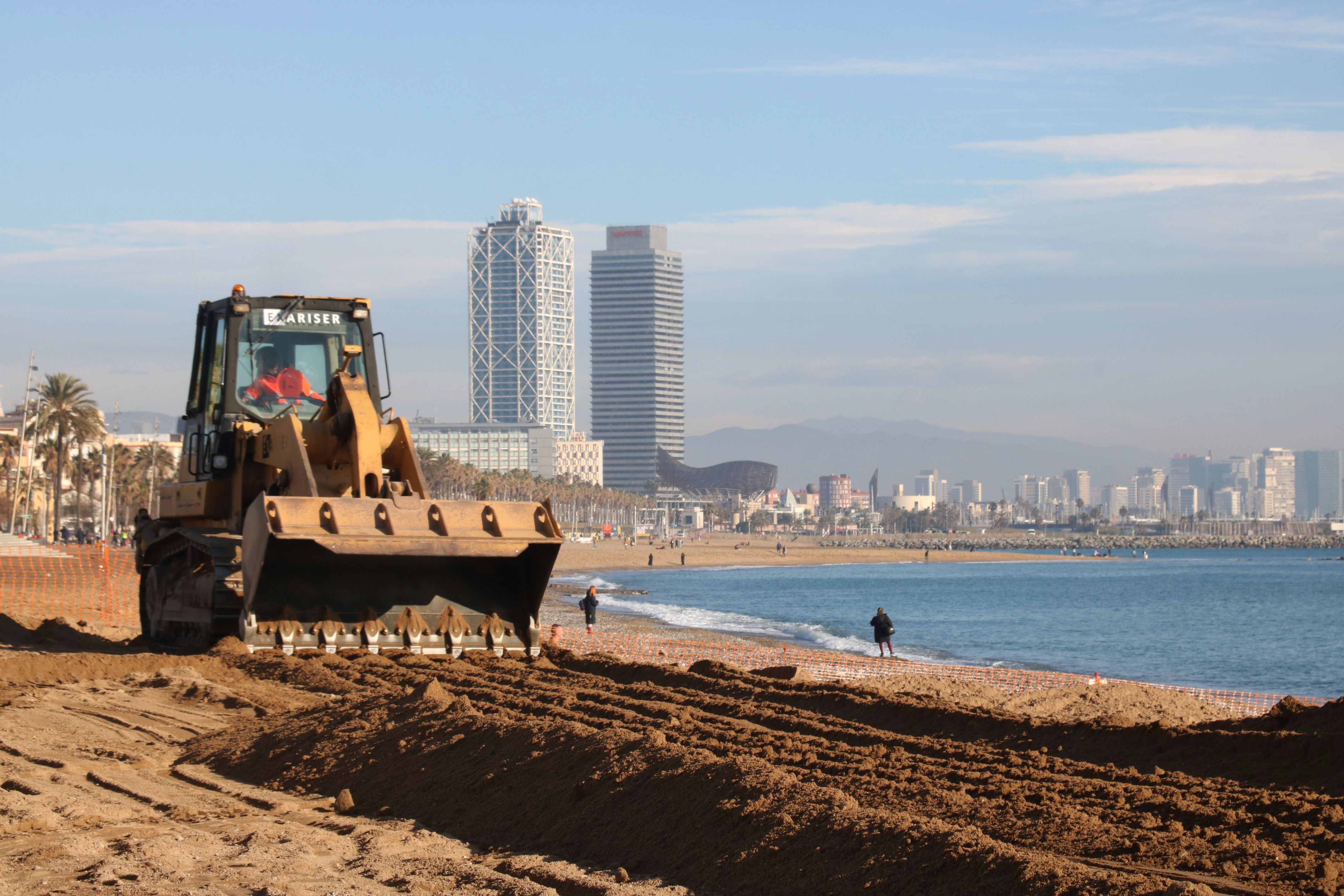 Una excavadora aplana la sorra a la platja de Sant Sebastià de Barcelona