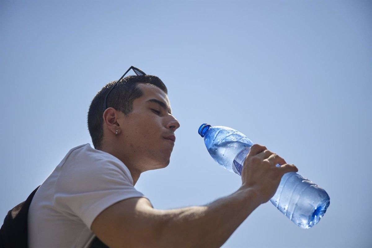Un jove beu aigua d'una ampolla de plàstic