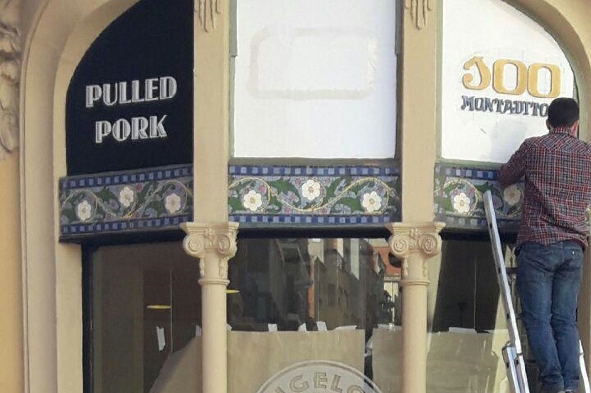 Operaris col·locant els cartells de la nova hamburguseria a Cal Sastre d'Olesa.