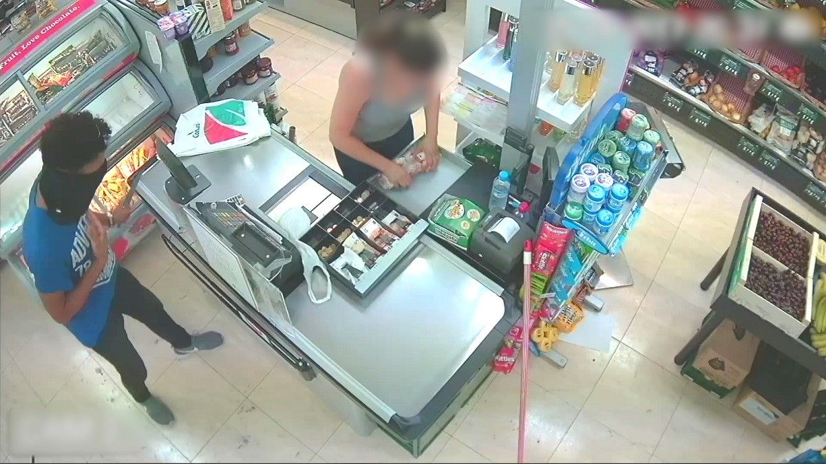 Imatge de la càmera de seguretat en què es pot veure com la detinguda, que feia de caixera, treu feixos de bitllets de la caixa registradora per ordre de l'atracador i còmplice en aquest robatori simulat en un supermercat de Martorell.