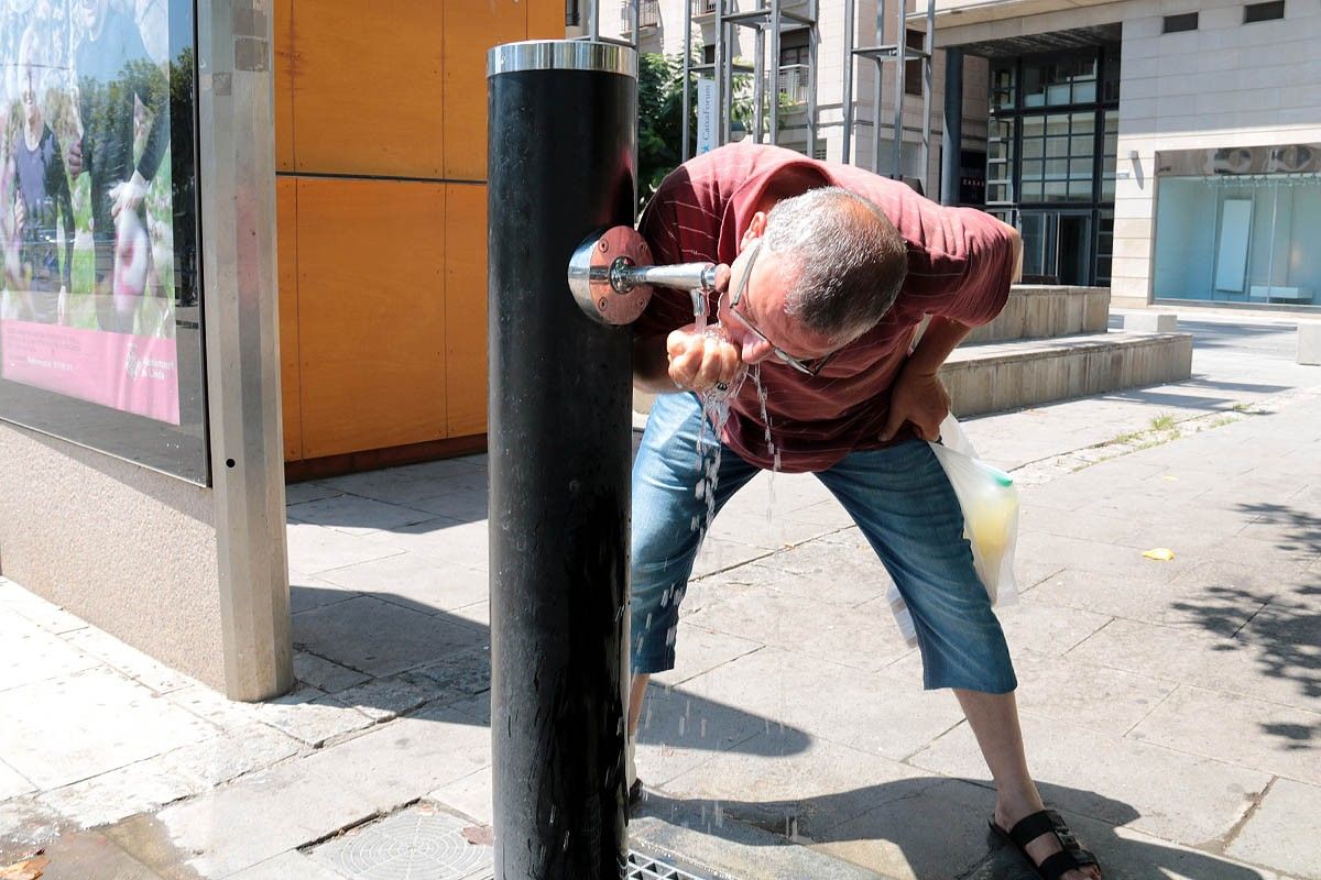Un home bevent aigua en una font.