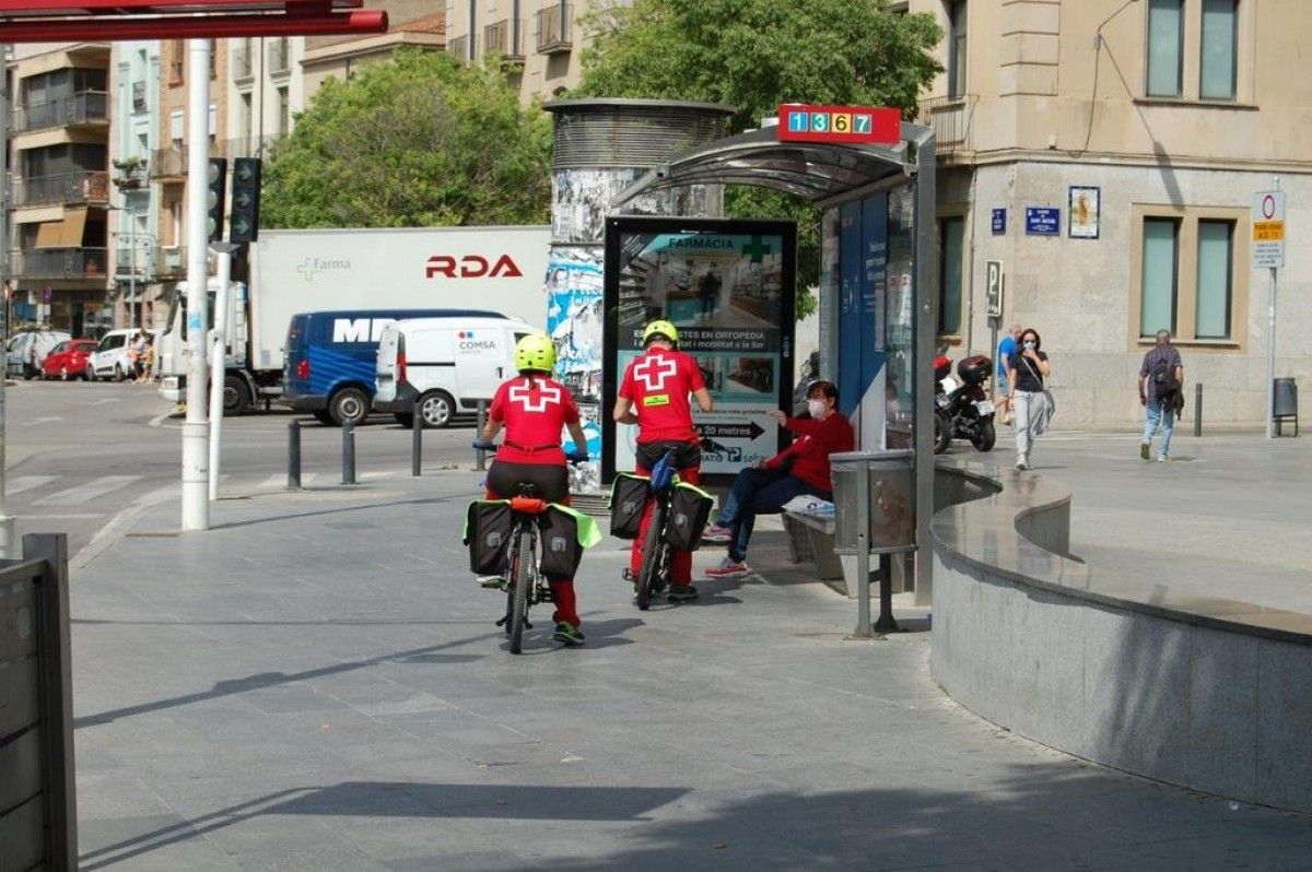 Dos voluntaris entreguen mascaretes en una parada de bus, aquest matí a Terrassa