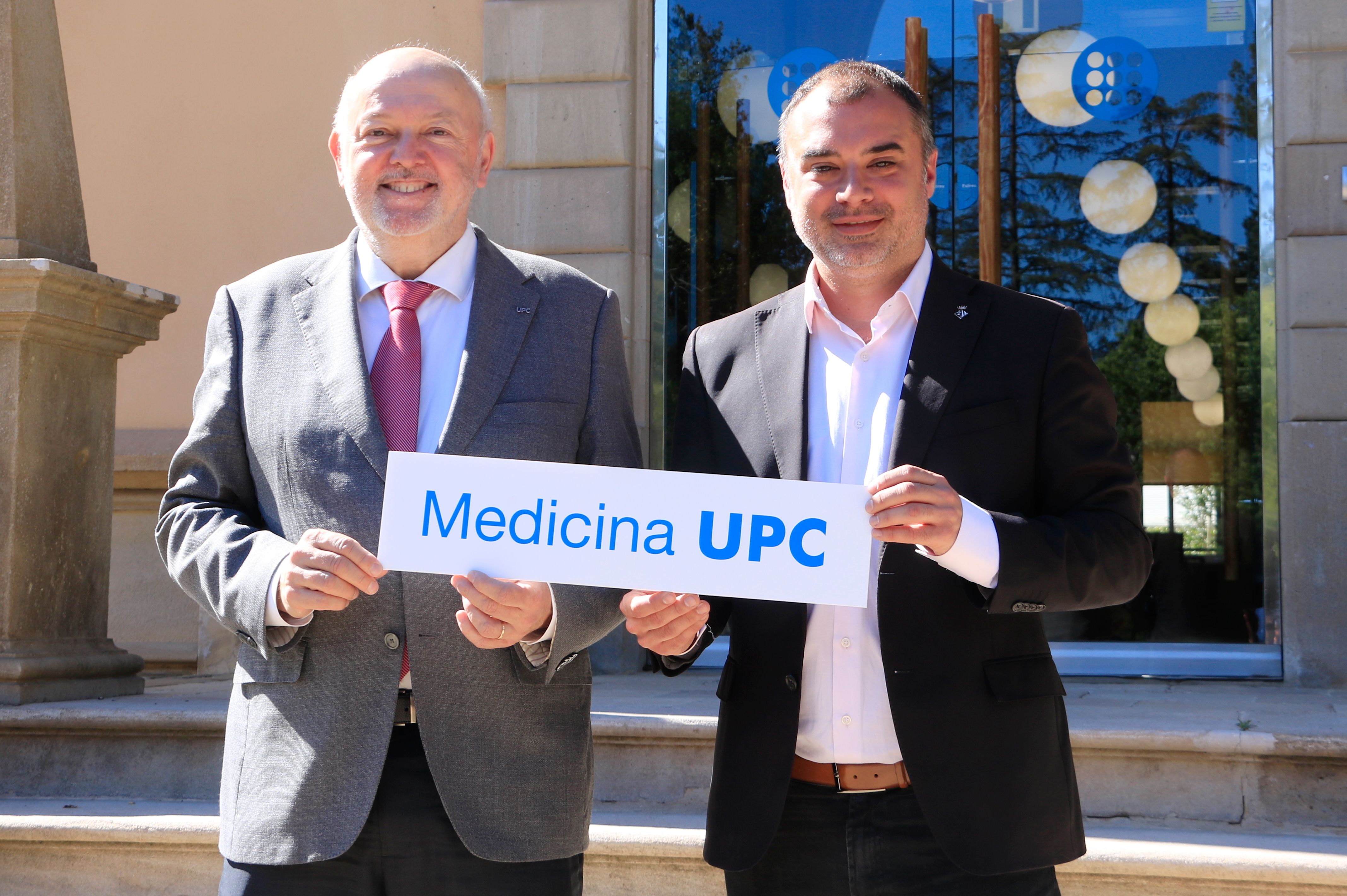 El rector de la UPC, Daniel Crespo, i l'alcalde de Terrassa, Jordi Ballart, aguanten un cartell que anuncia el projecte per crear nous estudis de Medicina, davant el rectorat de la universitat