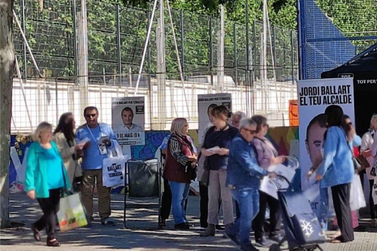 Membres de Tot per Terrassa repartint bosses amb el logo de la formació