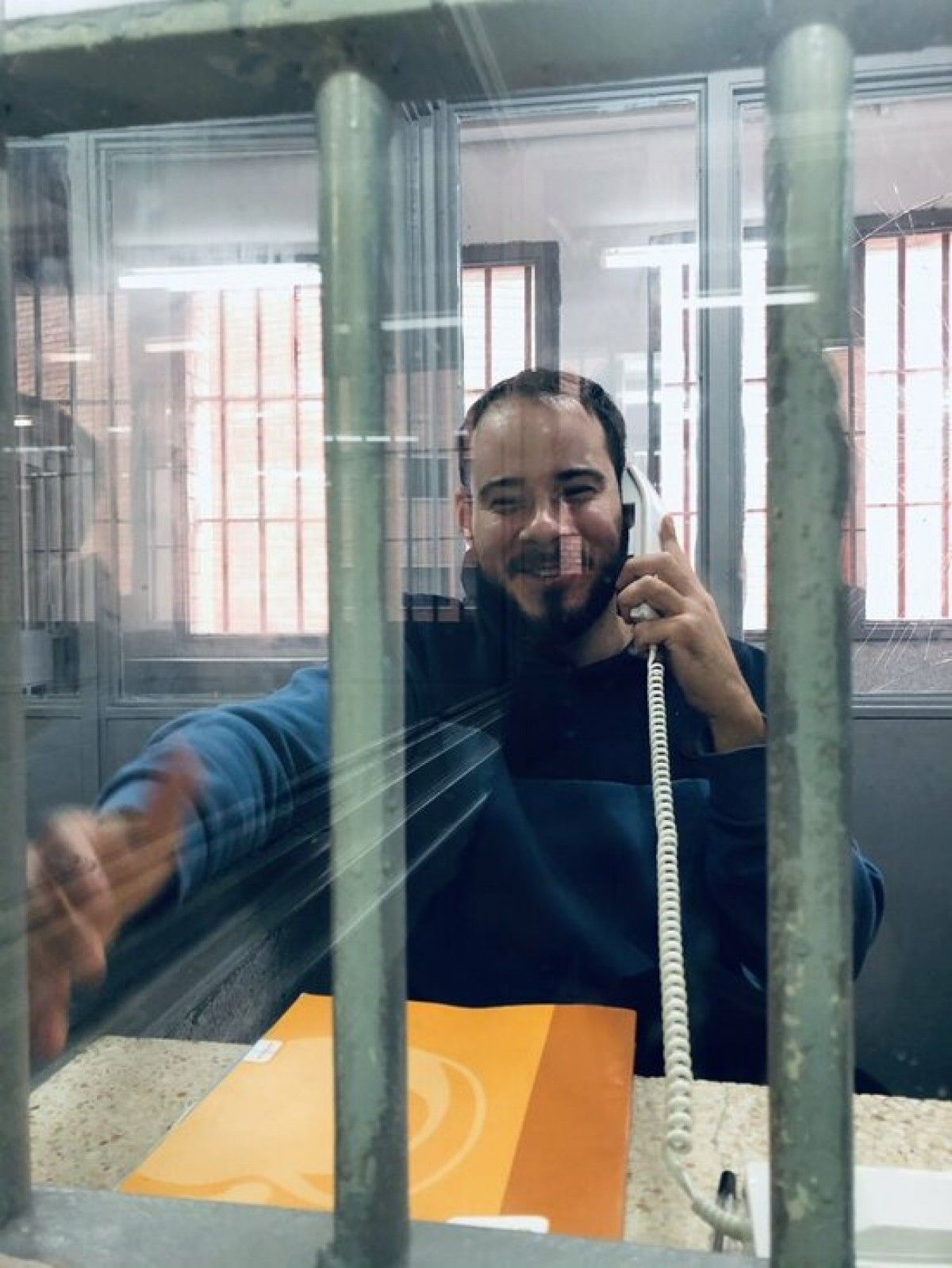 Pablo Hasel parlant a través d'un telèfon en una de les cabines de visita de la presó de Ponent