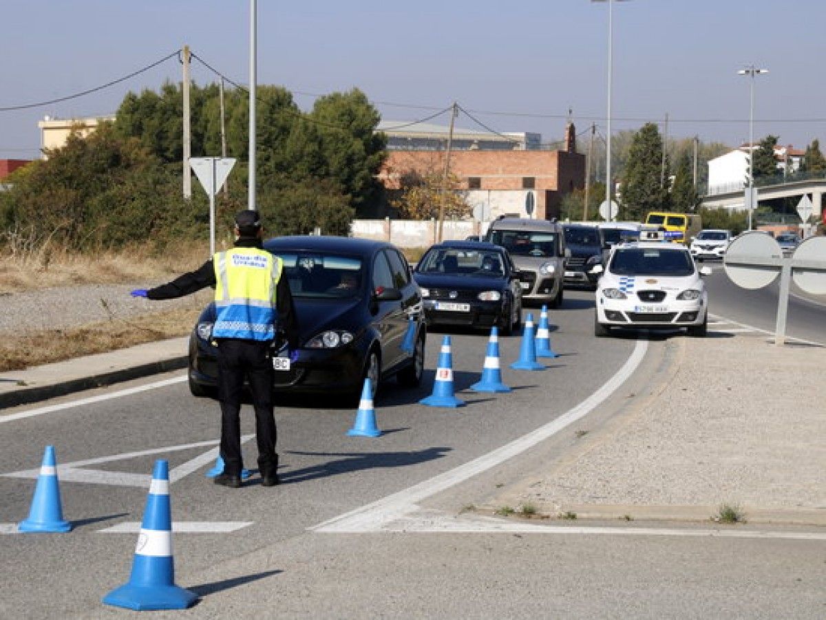 Un agent de la Guàrdia Urbana aturant un vehicle al control que han muntat a la N-230 direcció Lleida per les noves mesures restrictives per frenar la Covid-19.