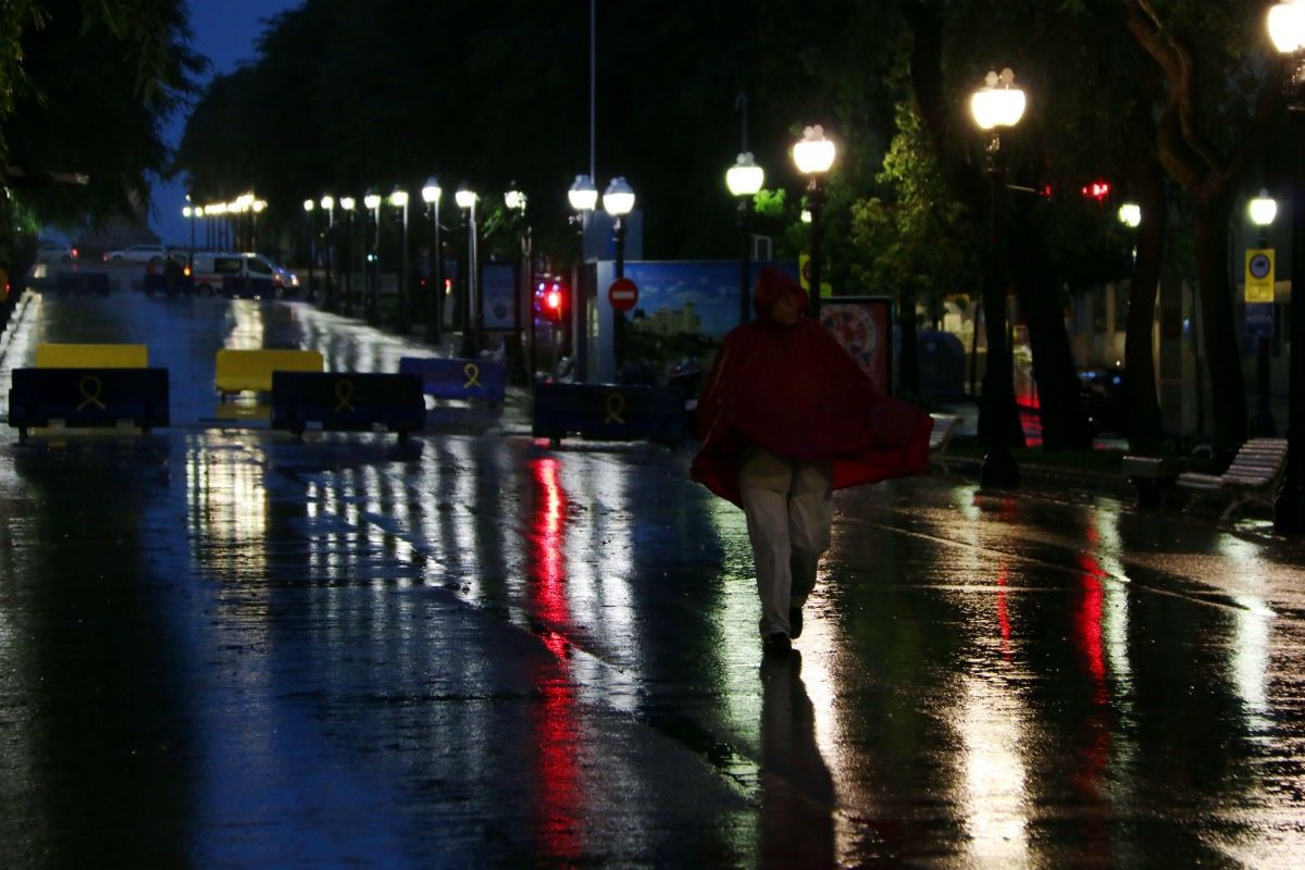 Un home amb un impermeable vermell sota la pluja intensa