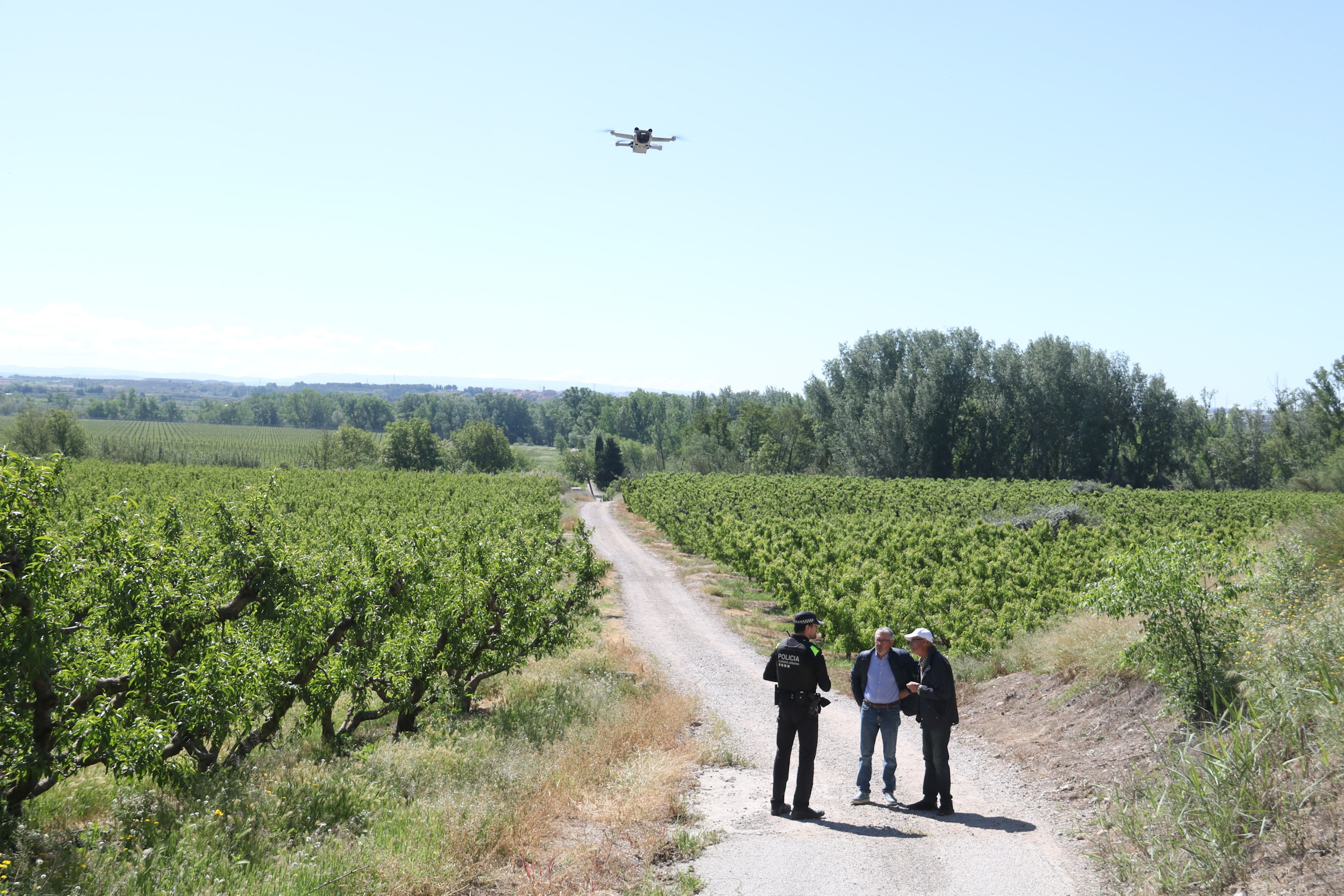 Un dron sobrevola les finques de l'Horta de Lleida mentre un Guàrdia Urbà conversa amb dues persones
