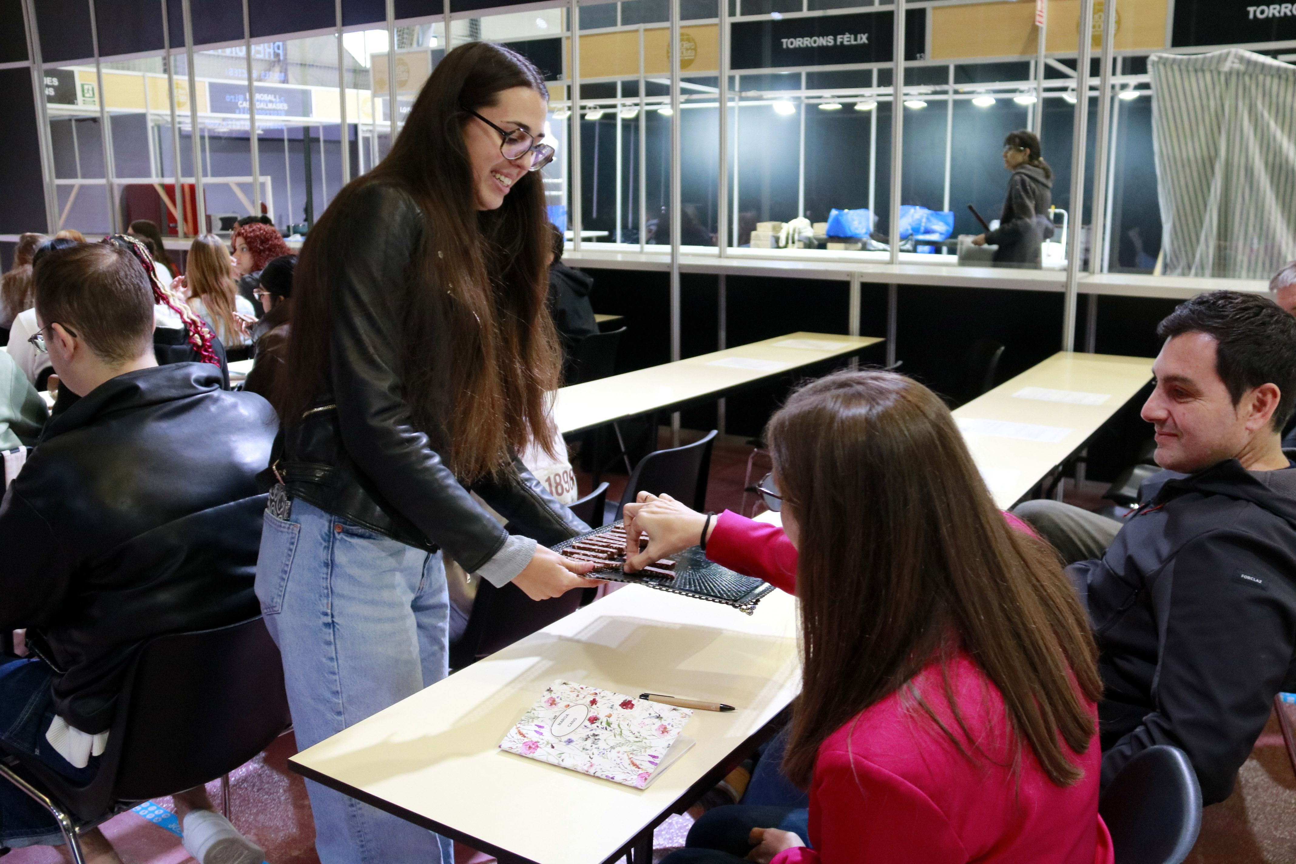 Una estudiant agafa un tast de torró a la jornada formativa l'Acadèmia del Torró