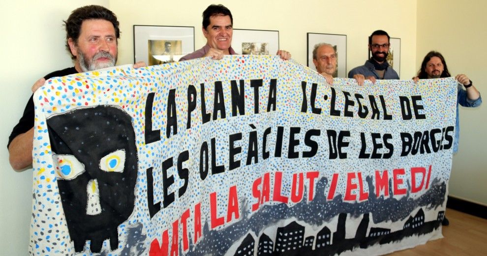 Representants d'Ipcena i veïns de les Garrigues amb una pancarta contra les emissions