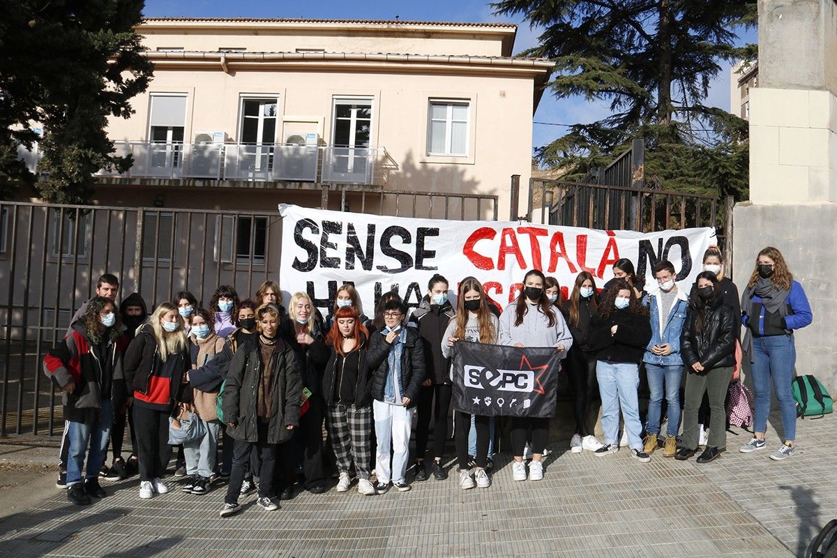 Estudiants de secundària davant del cartell que membres del SEPC han penjat davant l'Institut Màrius Torres de Lleida.
