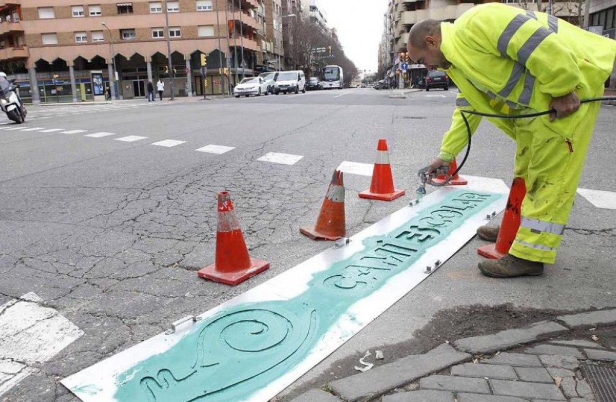 Un operari pintant un camí escolar de Lleida
