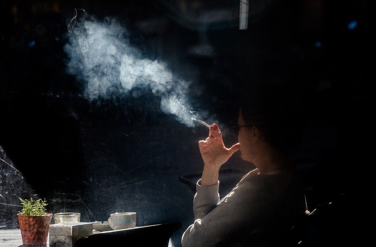 Una dona fuma una cigarreta en una terrassa 
