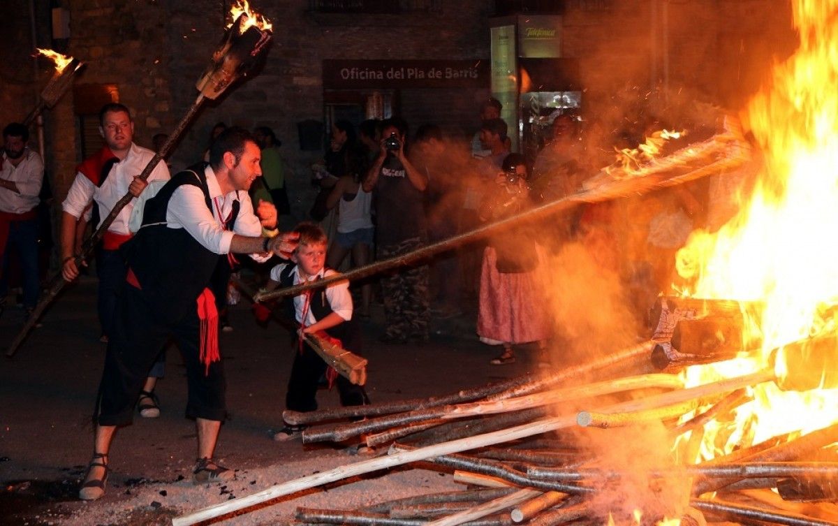 Un fallaire adult de la Pobla de Segur ensenya a un jove fallaire a llençar la falla a la foguera
