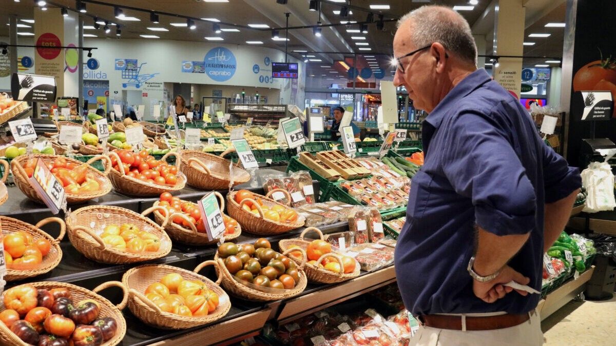Un home compara els preus de la verdura