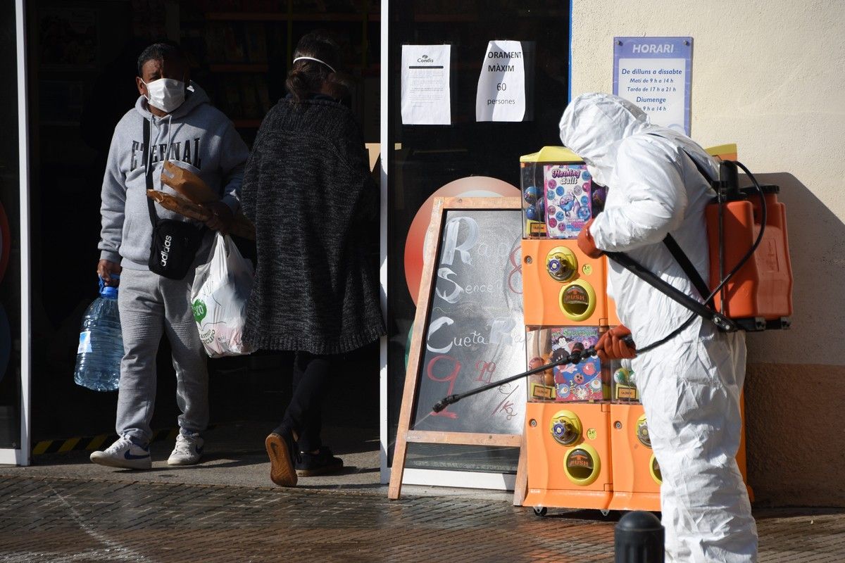 Un treballador municipal desinfectant a l'entrada d'un supermercat