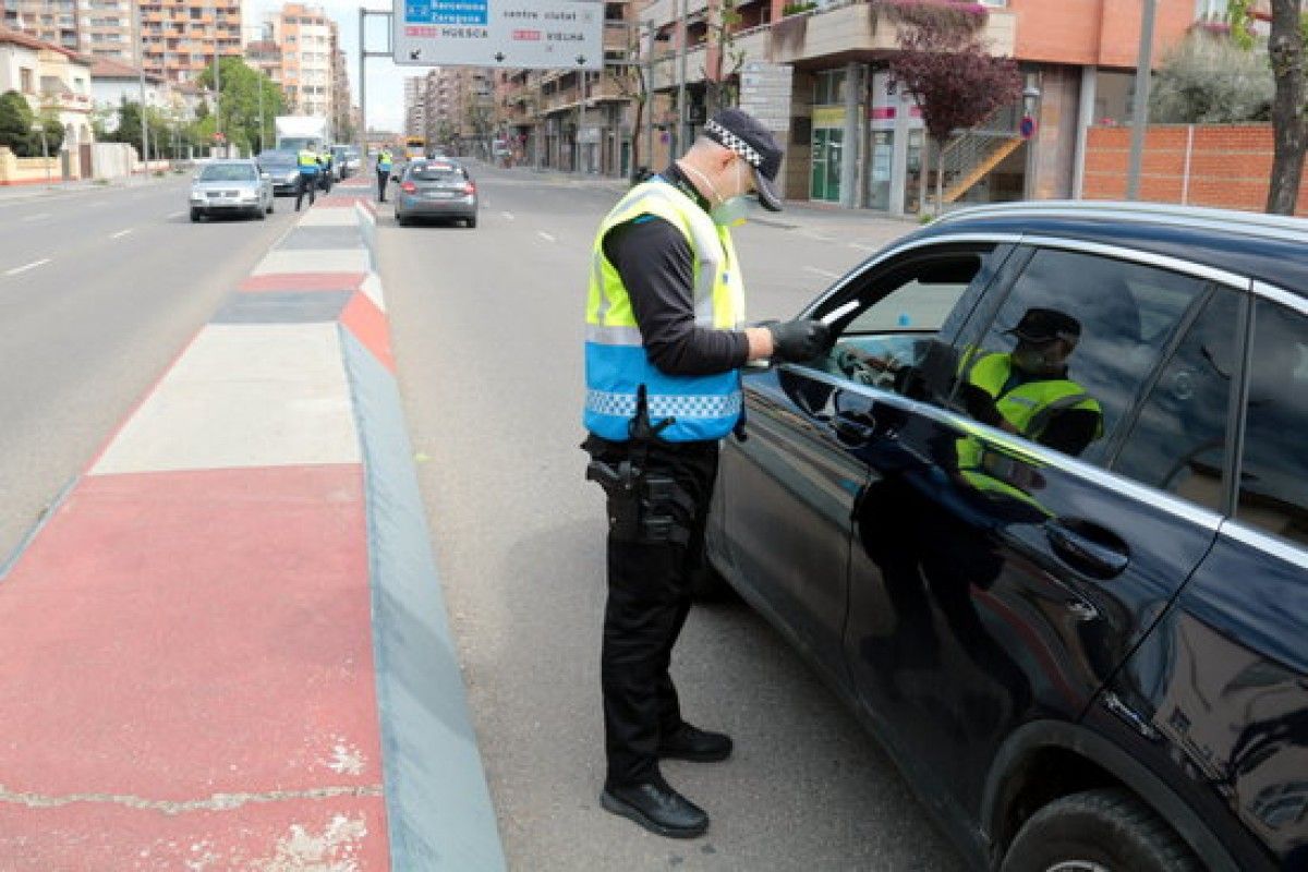 Un agent de la Guàrdia Urbana de Lleida parla amb el conductor d'un vehicle en un control per supervisar la mobilitat durant l'estat d'alarma